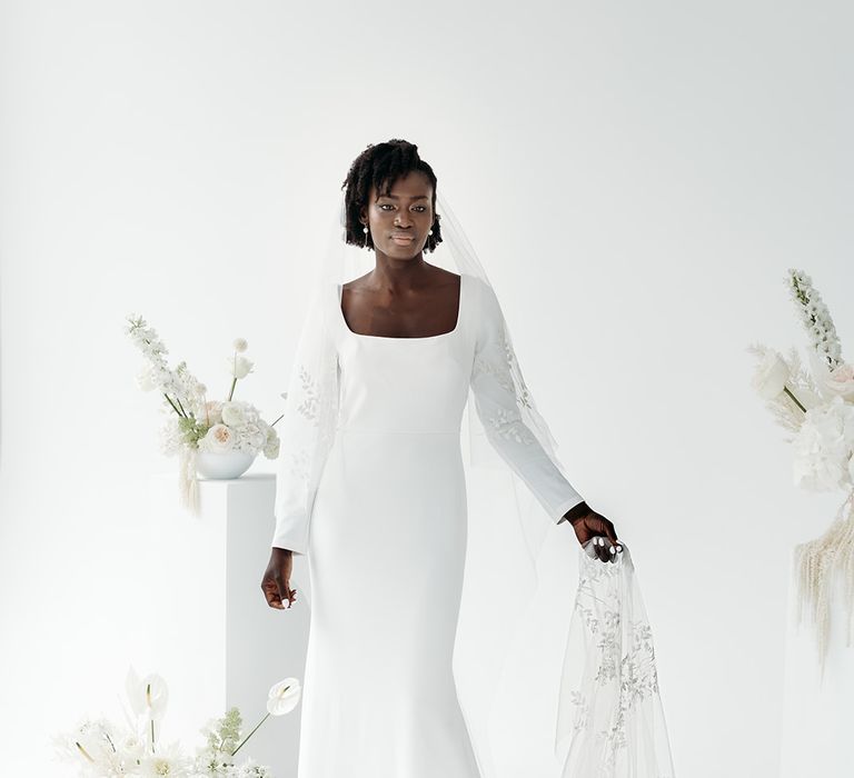 Black bride in a minimalist wedding dress with long sleeves wearing a cathedral length embroidered veil with leaf design