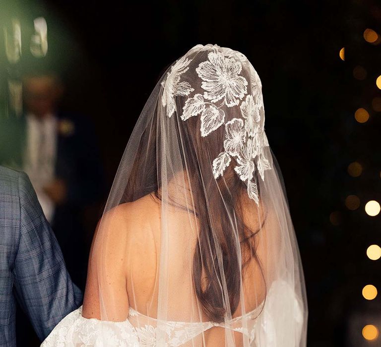 Bride with long dark hair in a cathedral length veil with lace detail on the cap to match the brides puff sleeve wedding dress