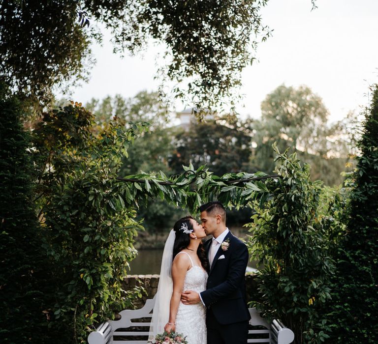 Bride and groom kissing portrait with the brides embellished wedding dress fanned out showing her long wedding train 