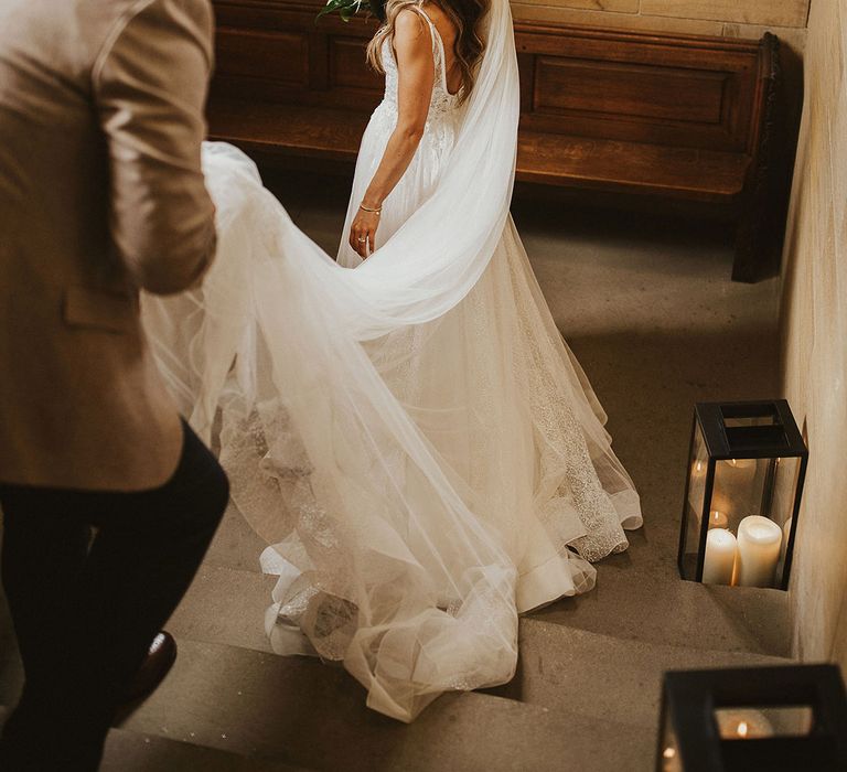 Groom holds brides veil as they walk down the steps with one another