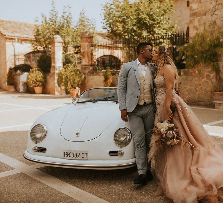 Bride & groom stand beside car on their wedding day