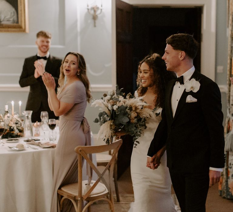 Bride & groom walk together as their wedding guests watch on