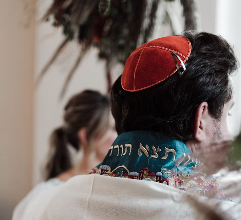 Groom in traditional Jewish wedding attire with red kippah during interfaith wedding ceremony at Iscoyd Park