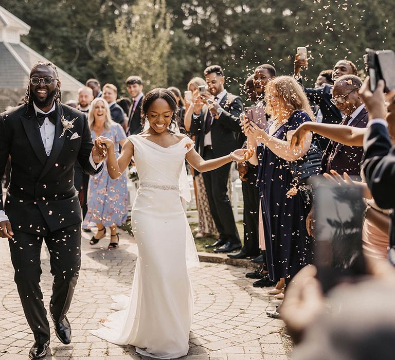 Bride & groom walk down the aisle as confetti is throw around them at Hayne House outdoors 