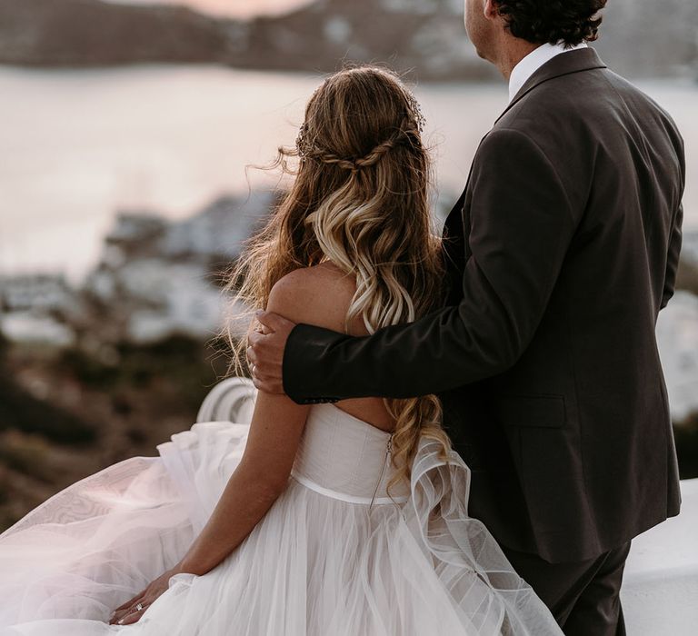 Bride & groom look across the sea as the sun begins to set on their wedding day