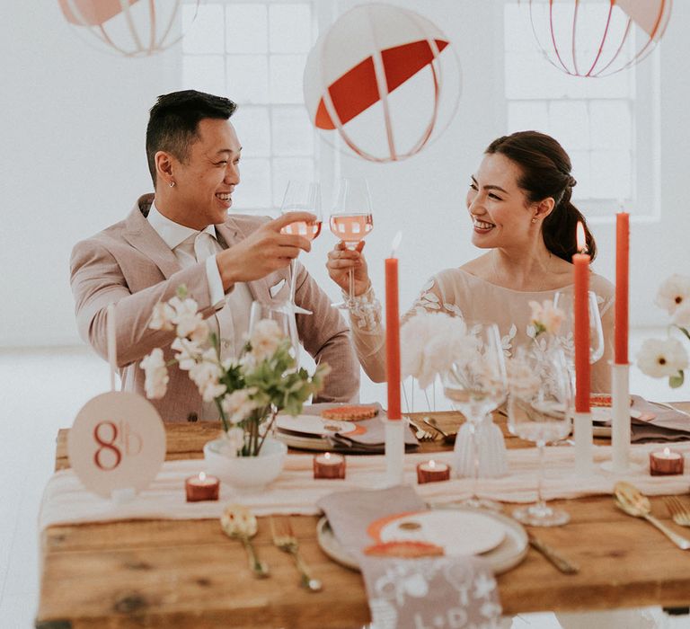 Bride & Groom cheers with wine as they celebrate at their asian inspired wedding decor