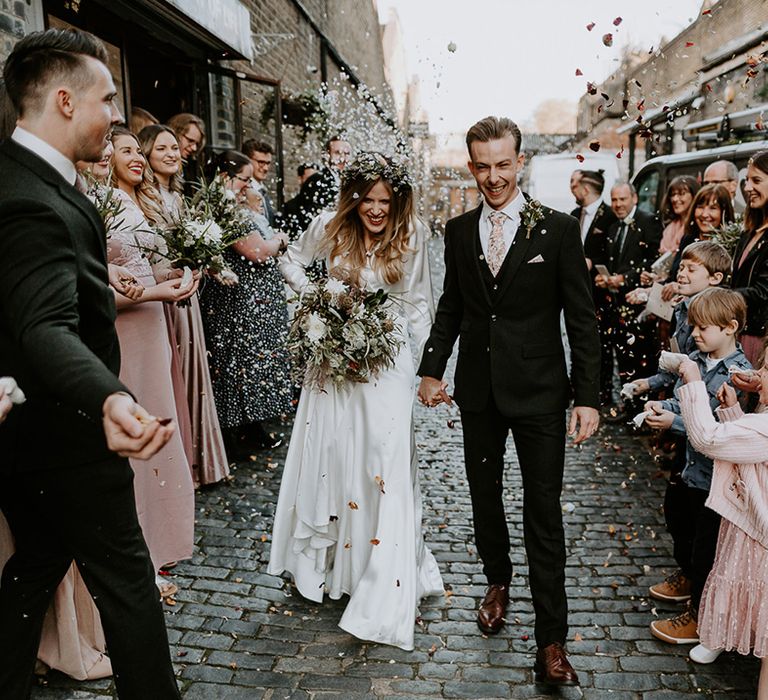 Bride & groom walk through confetti outdoors on their wedding day