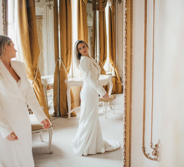 Bride looks at herself in the mirror wearing Zara jacket and sweetheart neckline wedding gown