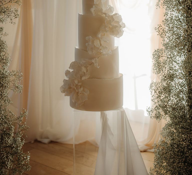 Tall five tier white wedding cake with cascading flower detail