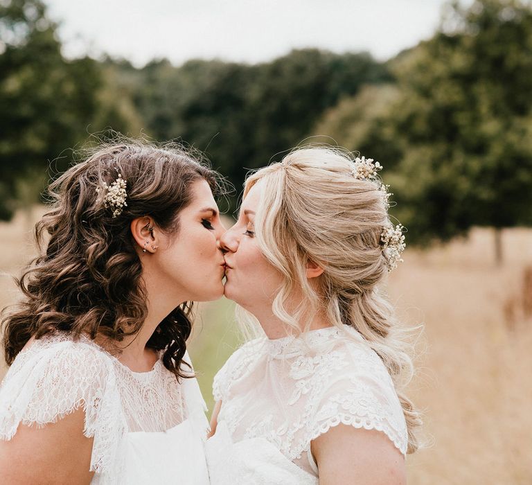 Brides in sheer high neck white wedding dresses share a kiss