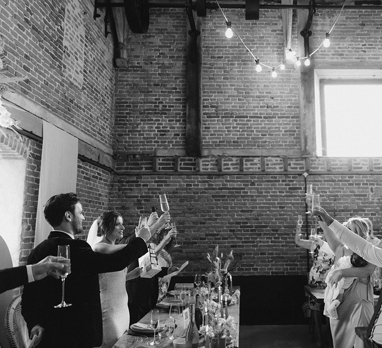 Bride and groom and the top table raise a toast as the rest of the wedding guests raise theirs too 