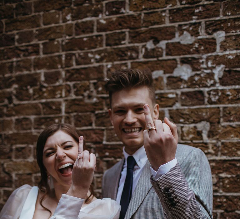 Bride and groom raise their ring fingers to show off their new wedding bands 