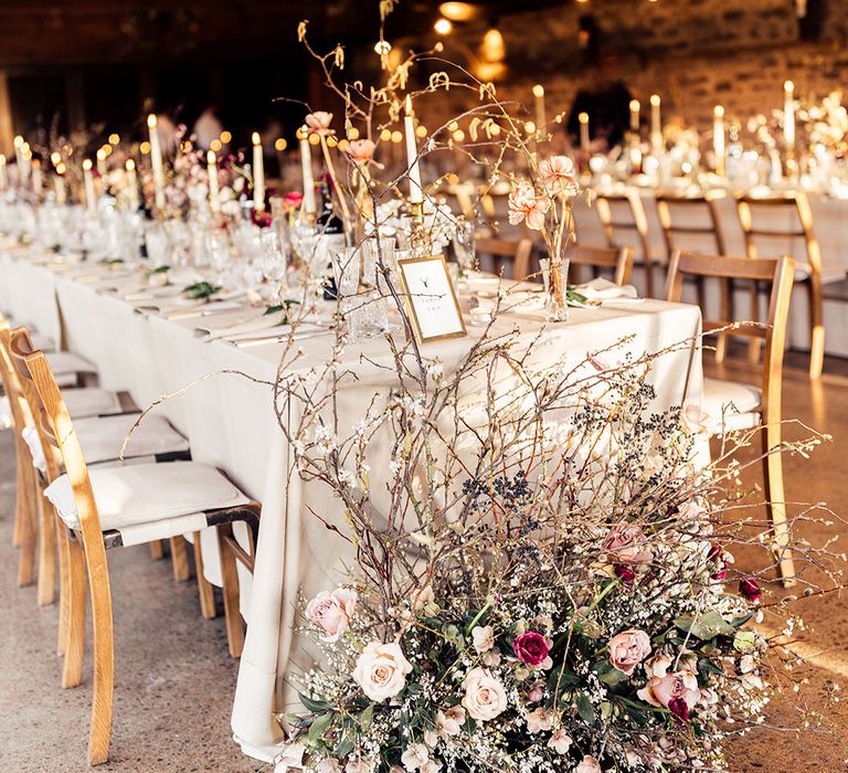 Long banquet tables with white tablecloths and white candles for classic style wedding with flower cloud decoration 