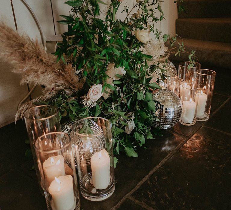 Roses and foliage flower decor with dried grasses with disco balls and white pillar candles