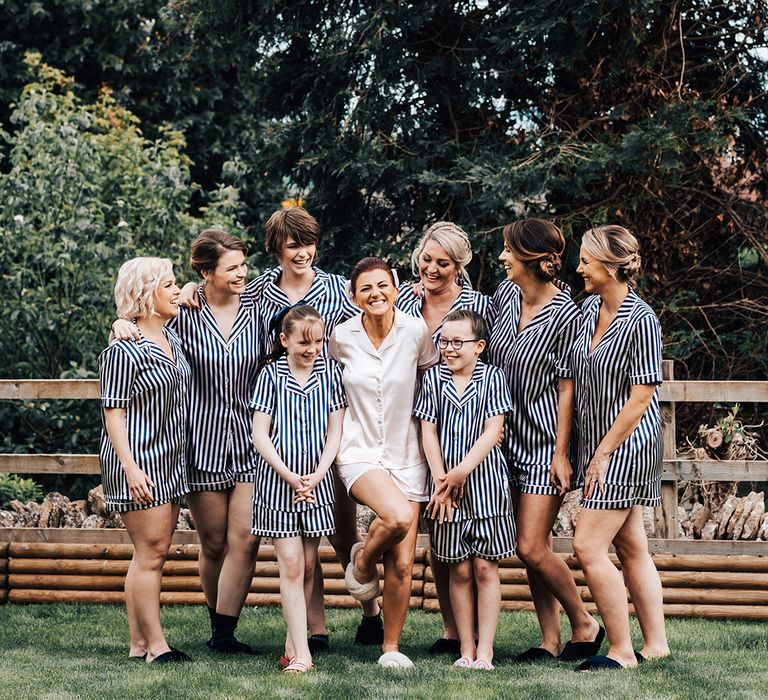 Bride in pink satin pyjamas with bridal party in matching blue and white striped pyjamas 