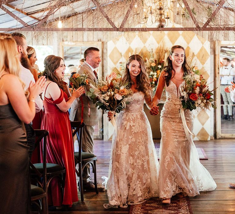 Brides walk back down the aisle hand in hand as a married couple 