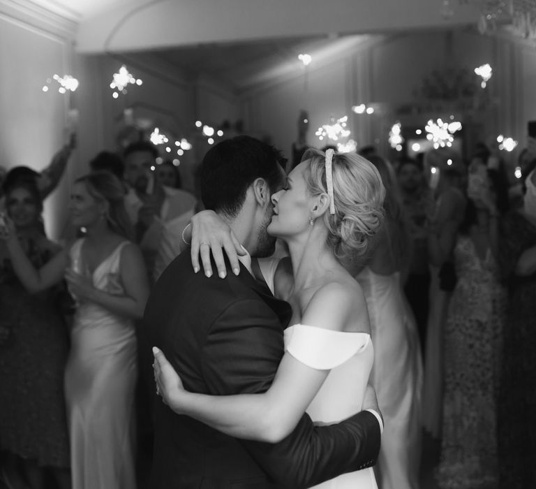 Bride & groom embrace as wedding guests hold sparklers around them during first dance 