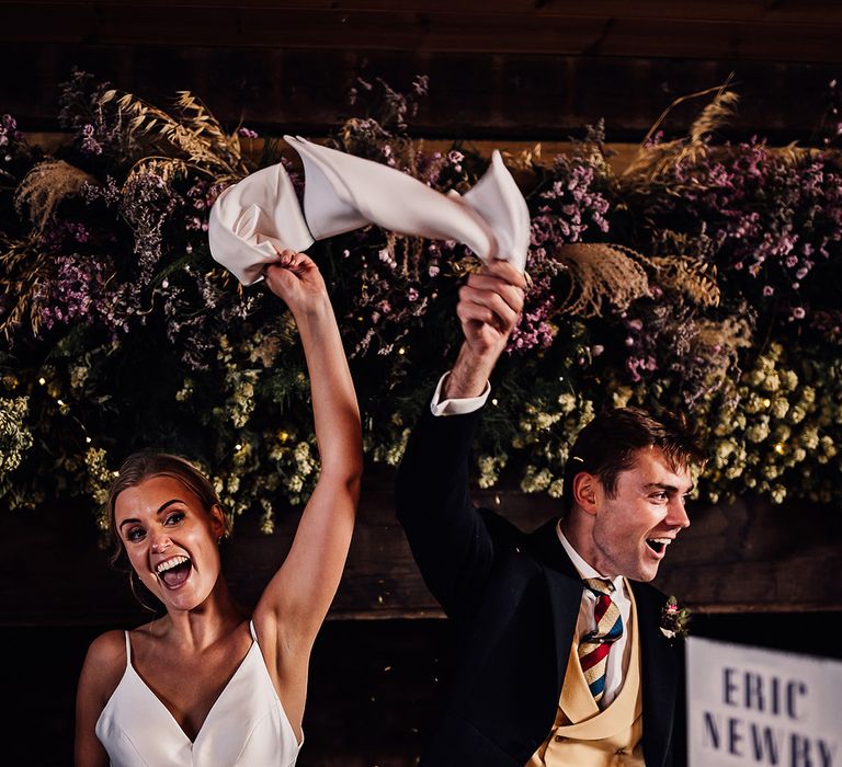 Bride and groom celebrate their marriage as they wave napkins in the air 