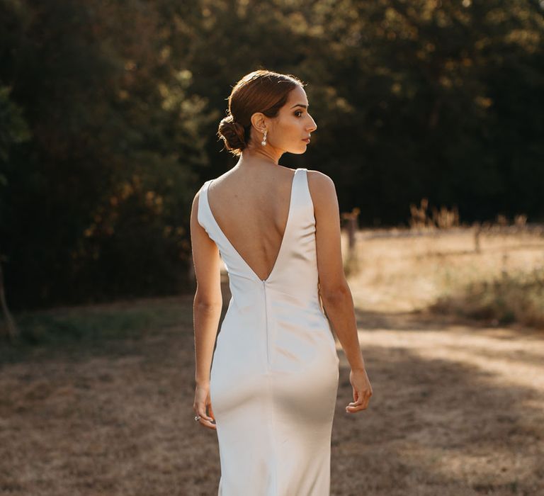 Bride wears silk fitted wedding dress with V-shaped back 