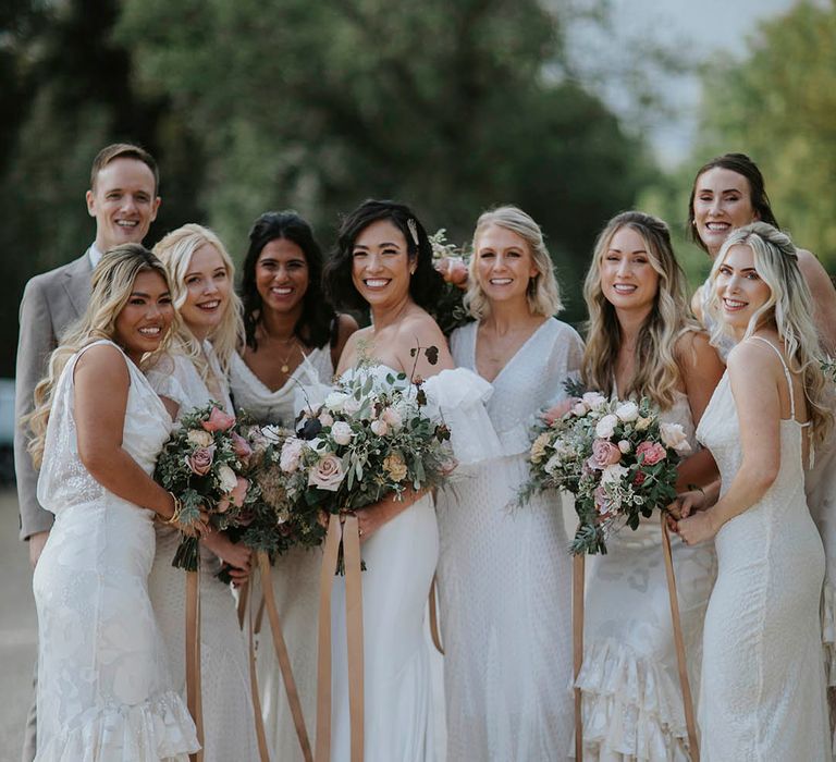 Bride in a puff sleeve wedding dress with a mixed gender wedding party with all the bridesmaids in white dresses in different styles 