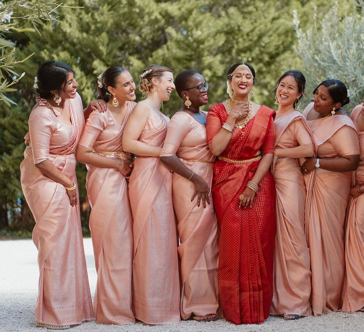 Bridal party with bride in a red lehenga and pink bridesmaids dresses