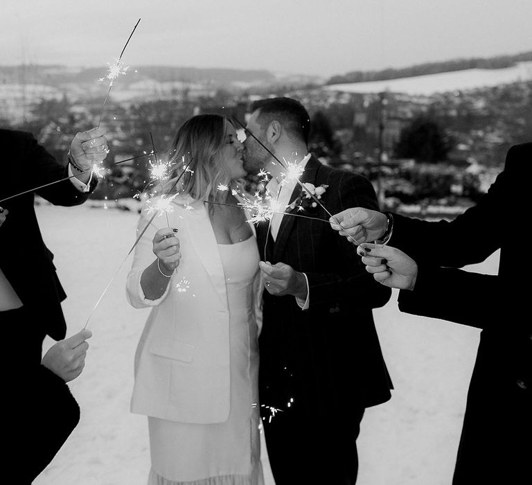 Magical sparkler moment for the bride and groom and their micro wedding with small number of guests out in the snow 