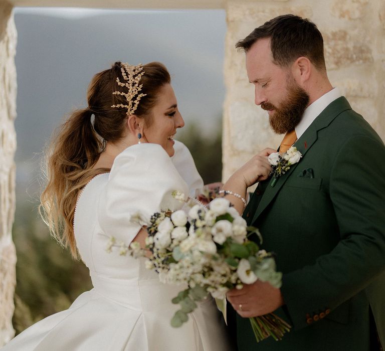 Bride in white satin dress and gold leaf bridal crown with groom in dark green groom suit at private villa wedding in Greece