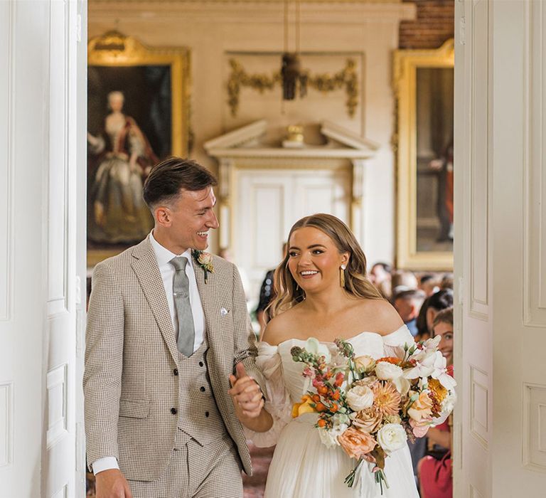 The bride and groom smiling brightly as they exit from their wedding ceremony 