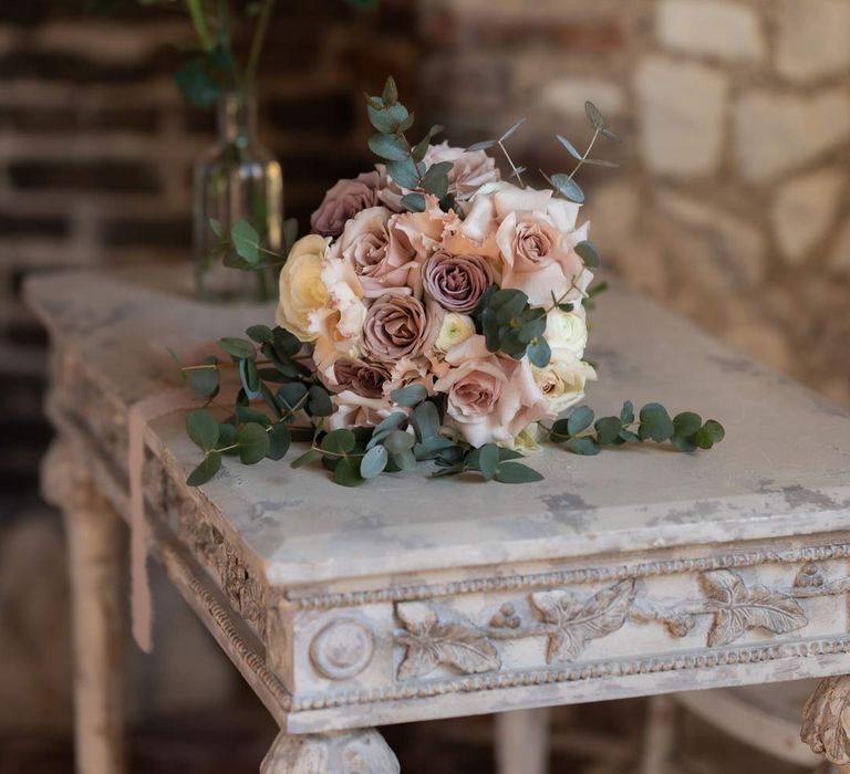 Blush garden rose and eucalyptus bridal bouquet on vintage rustic wedding table 