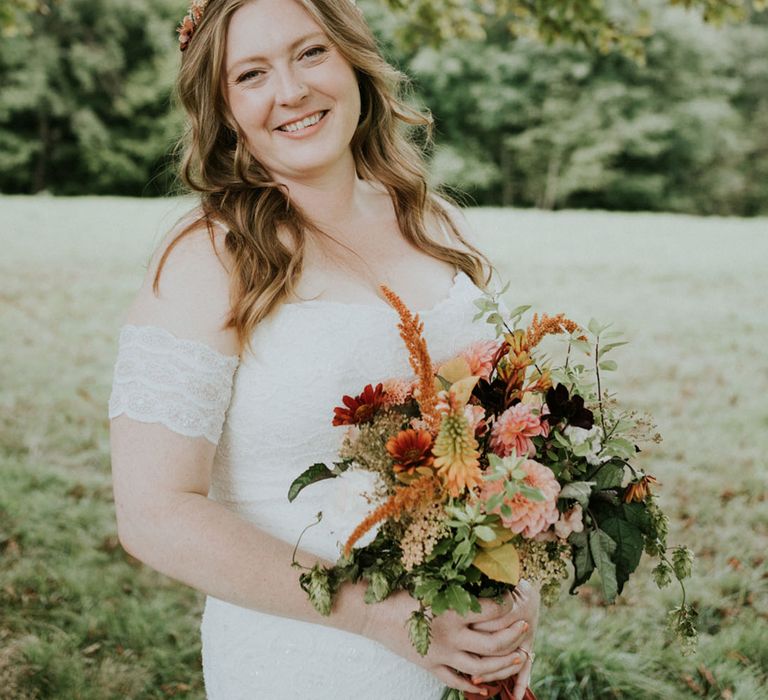 boho bride in a strapless lace wedding dress holding a wildflower bouquet 