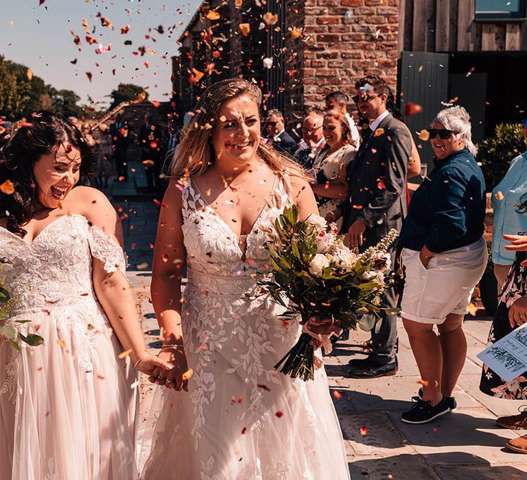 The two brides exit their ceremony to colourful confetti to celebrate the wedding 