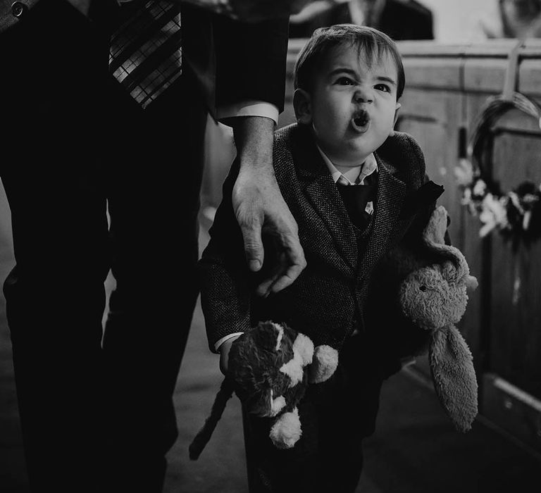 The bride and groom's little boy walking down the aisle with teddy bears 