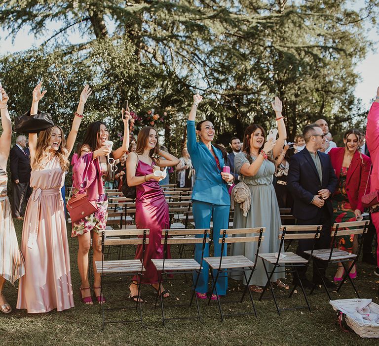 wedding guests raising their arms during the outdoor Italian villa wedding ceremony