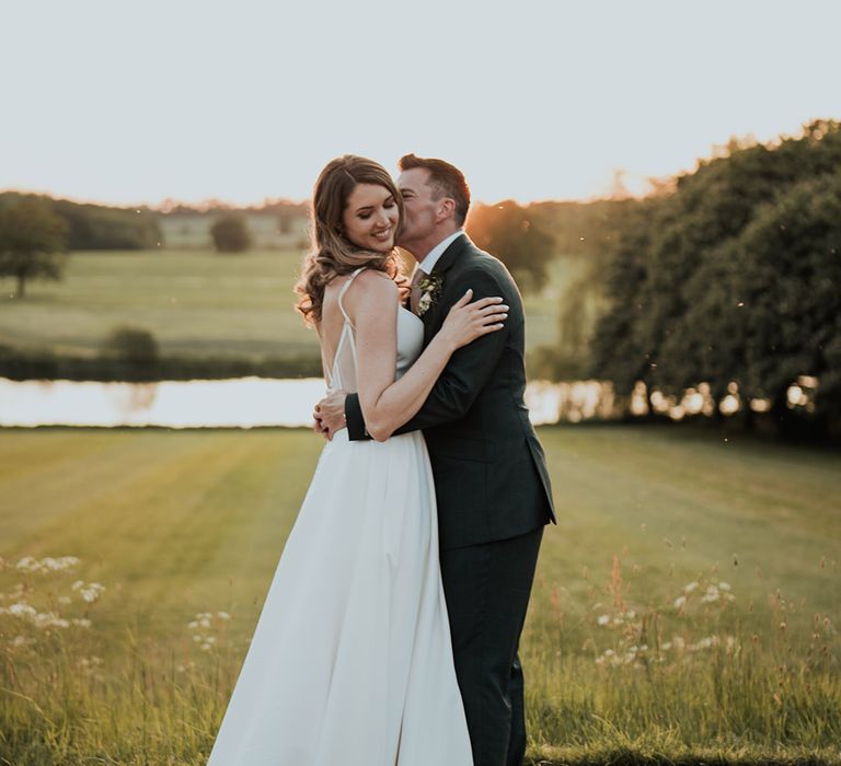 Kelmarsh Hall and Gardens wedding venue with the groom kissing the bride's cheek 