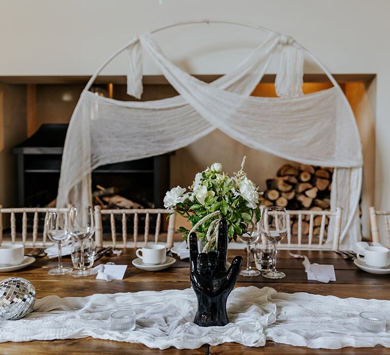 Wooden moongate with white drapery sits behind the top table at the bride and groom's seats 