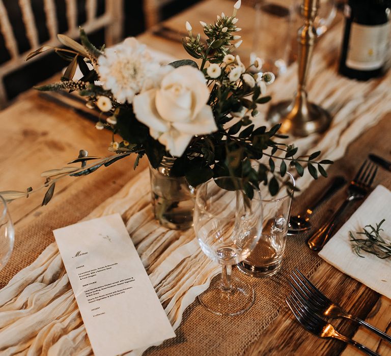 White roses in bud vases decorating the tabelscape with a neutral table runner 