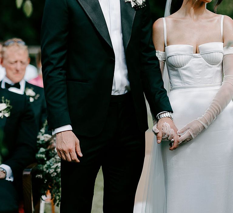 Bride holding hands with the groom at the outdoor ceremony 