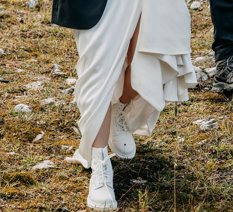 Bride in white boots to walk around the rocky terrain and hike the mountains 