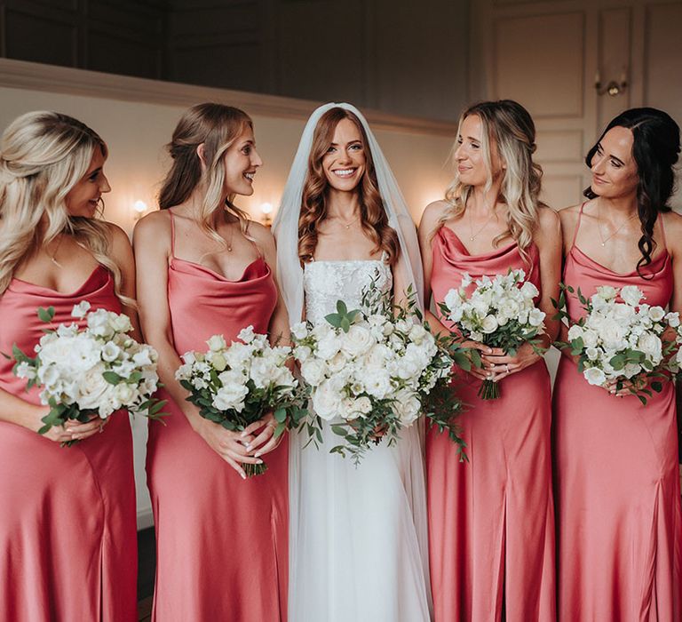 Bridal party wearing pink coral bridesmaid dressses with white shoes 