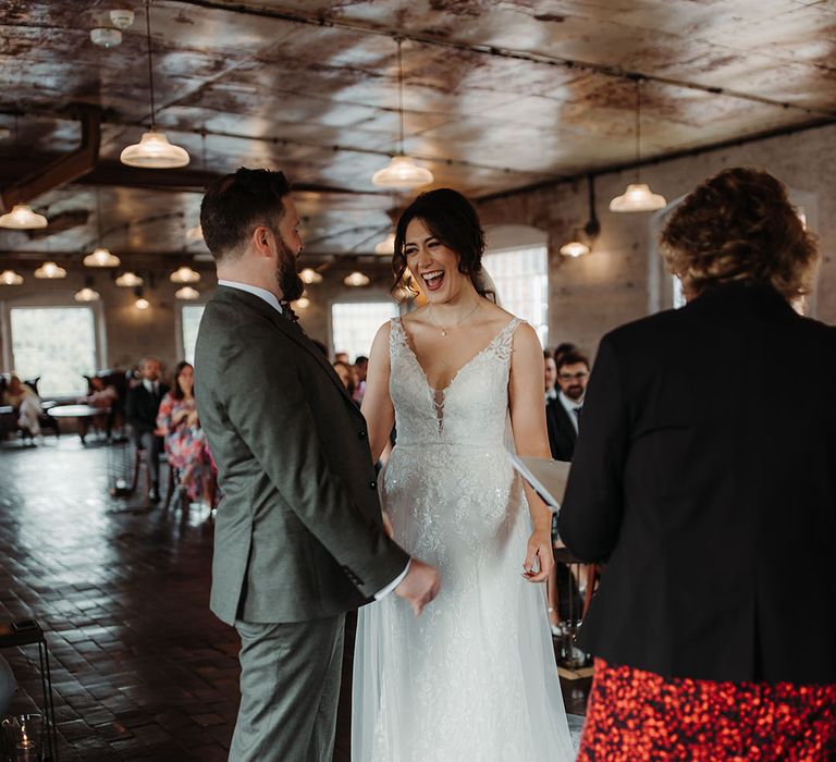 Bride in floral lace wedding dress with the groom in a green suit for their autumnal wedding 