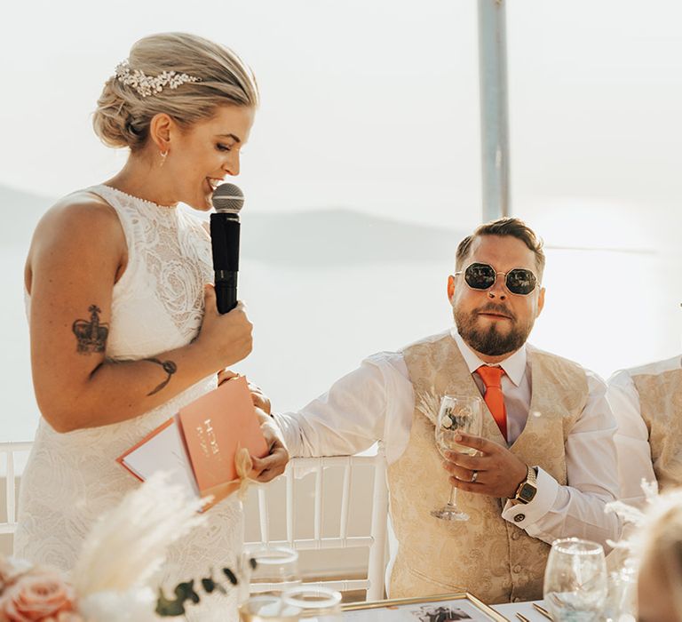 Bride stands as she reads out her bridal speech at the wedding breakfast in Santorini 