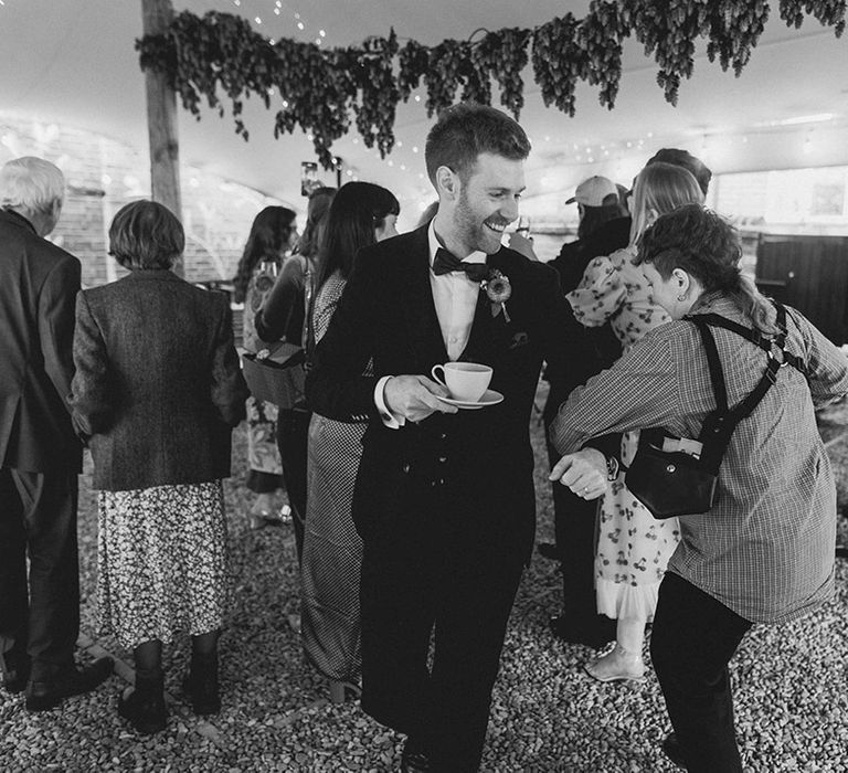 Pub wedding reception with groom dancing with guests holding a teacup and saucer 