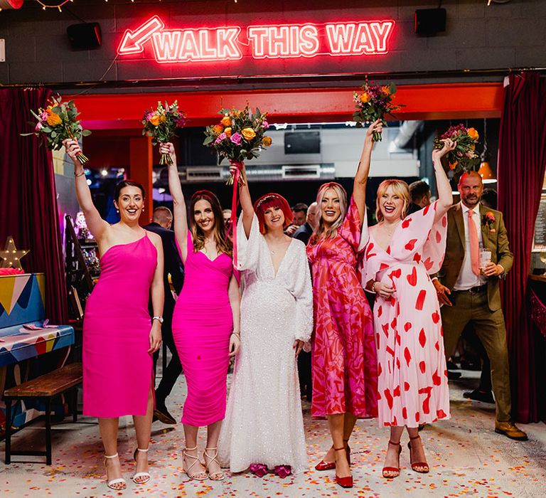 Bridal party wearing mismatched pink bridesmaid dresses with pink and orange wedding bouquet 