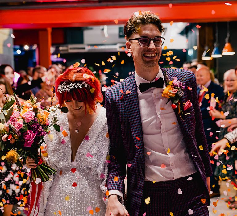 Confetti moment for cool and alternative bride and groom wearing a high street wedding dress and wedding suit 