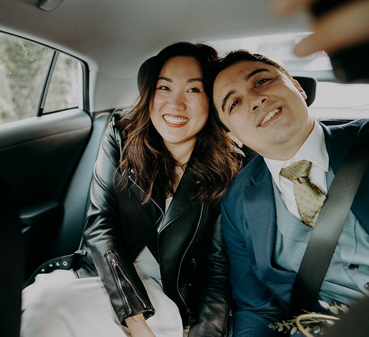 Bride and groom in the back of a taxi at city wedding