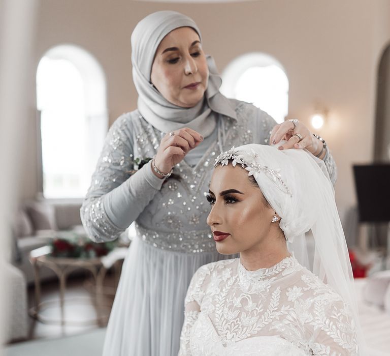 Mother of the bride in silver dress helping her daughter on the wedding morning 