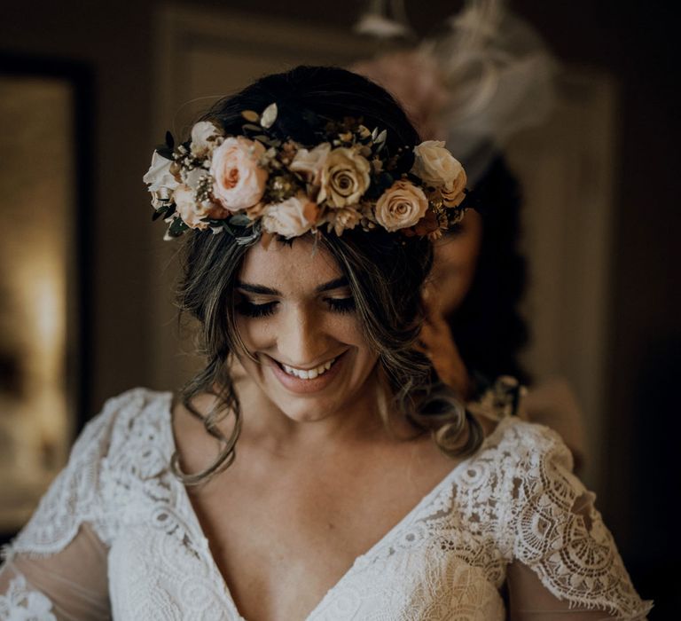 Smiling boho Bride with flower crown and v neck wedding dress looking down 