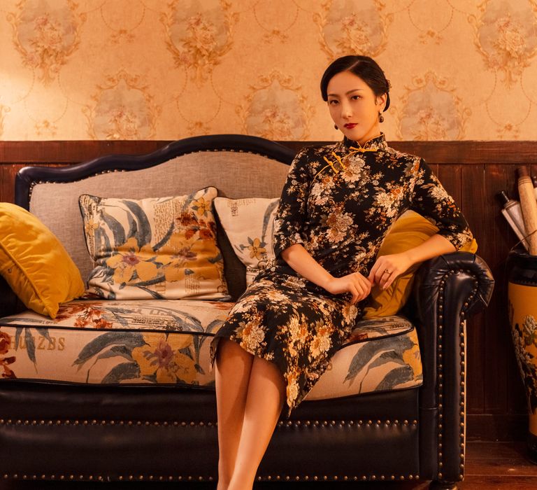 Bride-to-be leans back elegantly on sofa during engagement shoot