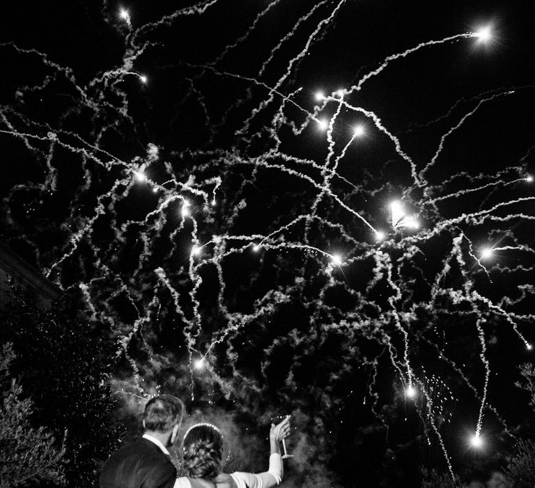 Bride in Elbeth Gillis gown stands arm in arm with groom watching fireworks at Euridge Manor wedding