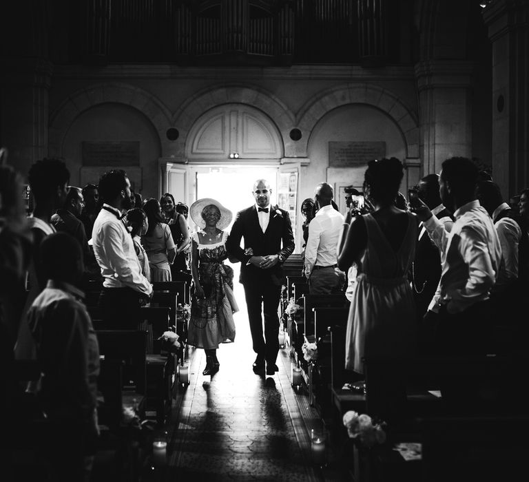 The groom making his entrance into the church with a woman on his arm